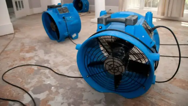 Blue air mover fan running on a bare floor
